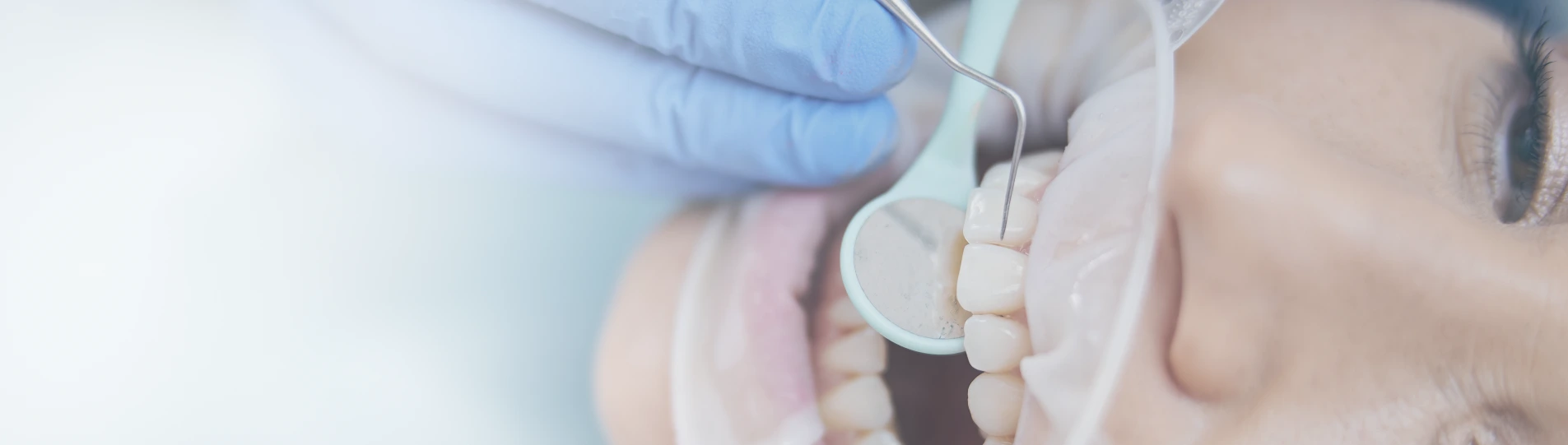 Dentist examining a patient’s tooth using a dental mirror and probe.